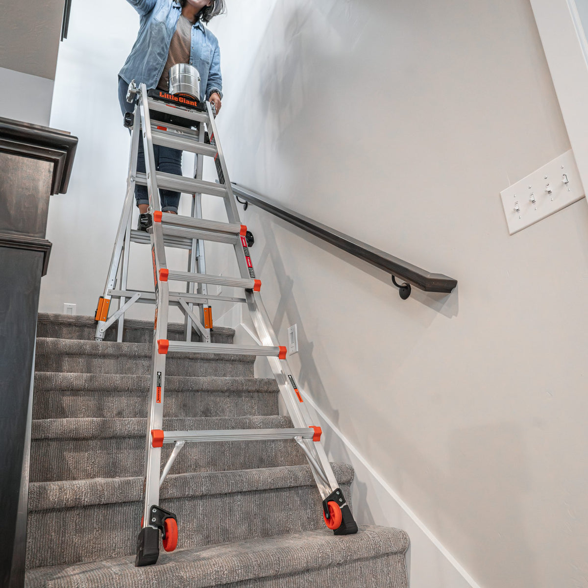 Leveler Mehrgelenkleiter auf einer Treppe, Person arbeitet an der Wand über dem Treppenlauf