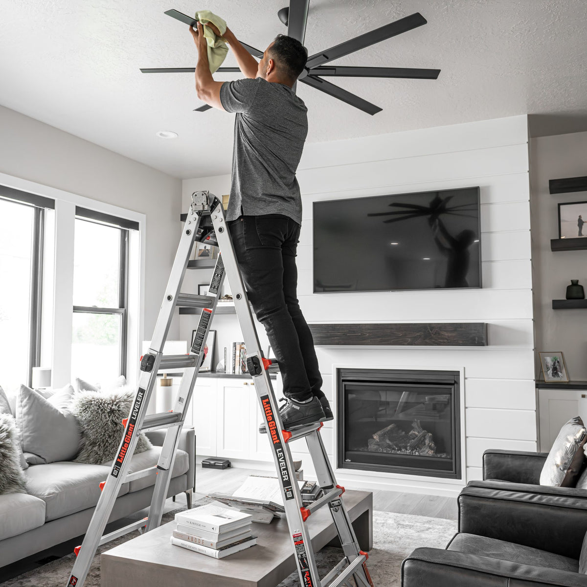 Leveler Mehrgelenkleiter im Wohnzimmer, Person montiert einen Deckenventilator