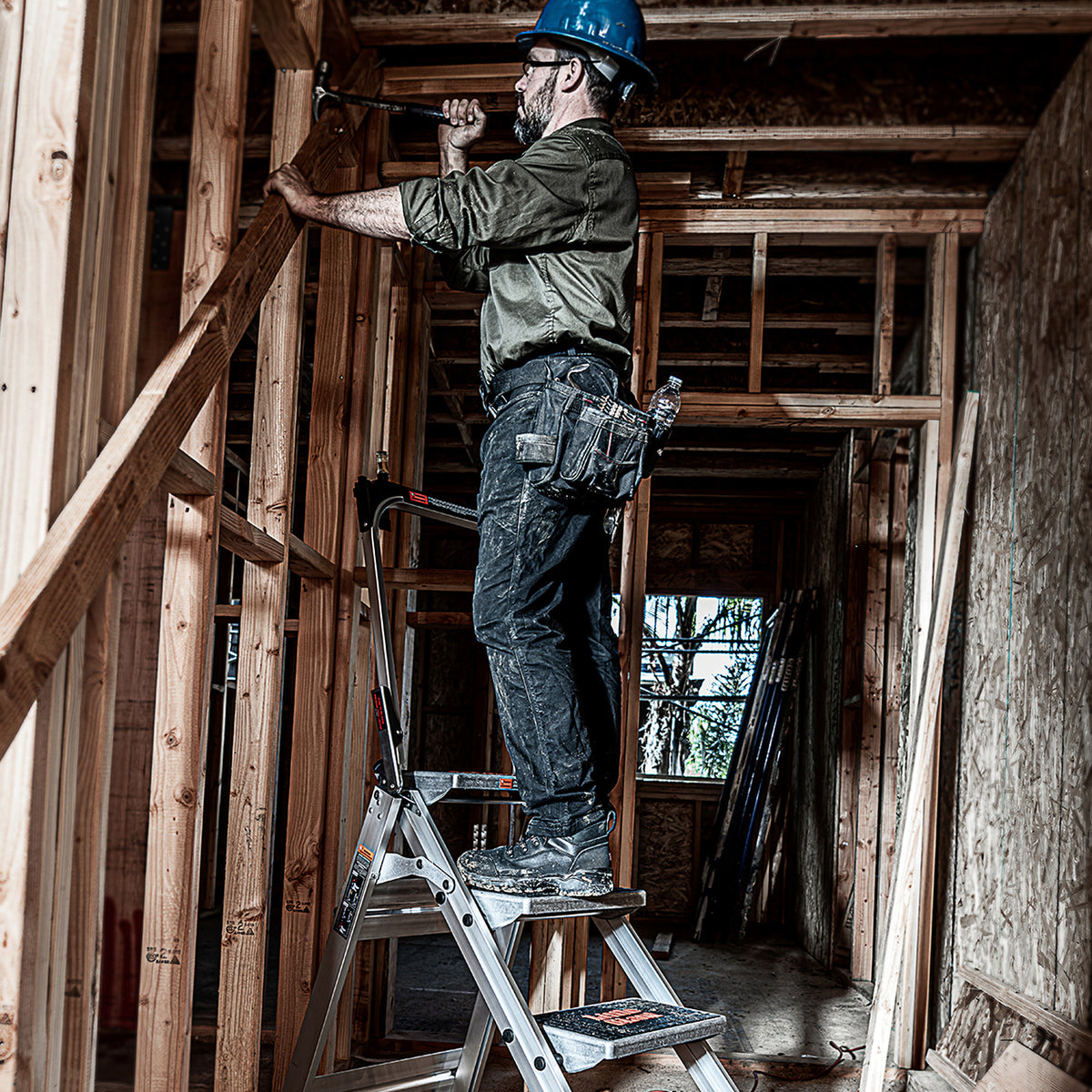 Handwerker arbeitet auf dem Safety Step an der Decke im Rohbau